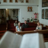 Individuals sitting in a church pew during a prayer session.